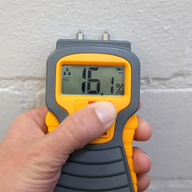 Pin moisture meter reading a wet wall during a water damage inspection in Alhambra