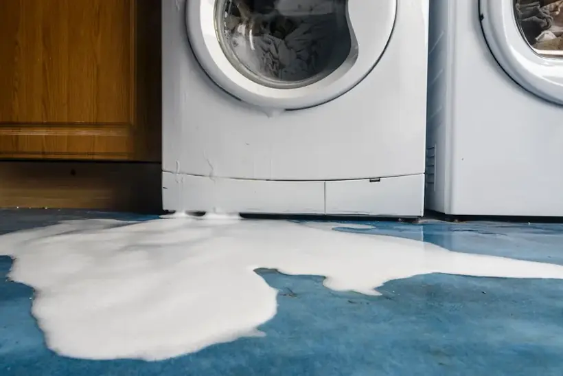 Water and suds spreading across the floor from a leaking washing machine